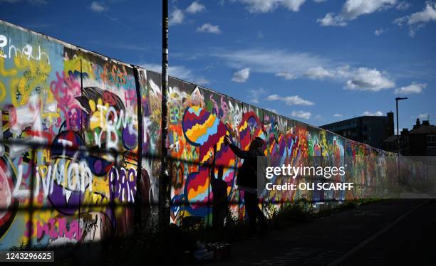 Street artists sprays grafiti art onto a wall in Shoreditch in east London on September 17, 2022.