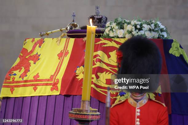 Royal guard stands next to the coffin of Queen Elizabeth II, draped in the Royal Standard with the Imperial State Crown and the Sovereign's orb and...