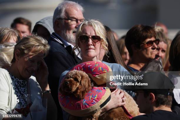 Woman carries a dog as she joins people gathered outside Buckingham Palace as people visit to pay respects to Queen Elizabeth on September 17, 2022...