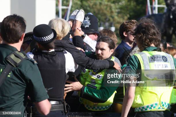 Member of the public is lifted over the barrier at Buckingham Palace by police and paramedics on September 17, 2022 in London, United Kingdom. Queen...
