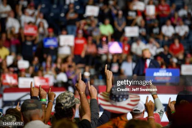 Audience members put their index finger up to symbolize America First while President Donald Trump speaks at a Save America Rally to support...