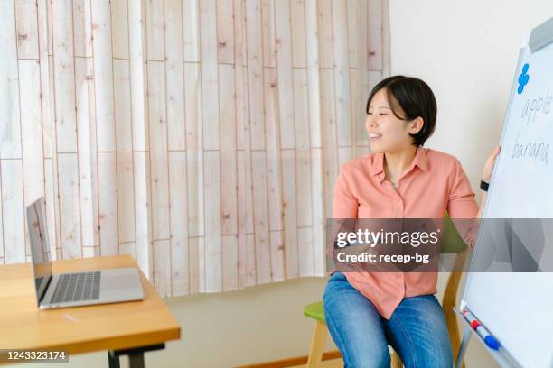 teacher teaching online via laptop at home - japanese people lesson english stock pictures, royalty-free photos & images