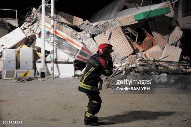 Rescuer speaks on cellphone in front of a collapsed building after an earthquake at Yuli Township in Hualien county, eastern Taiwan on September 18,...