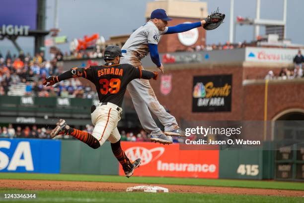 Thairo Estrada of the San Francisco Giants reaches first base ahead of a tag from Freddie Freeman of the Los Angeles Dodgers during the fifth inning...