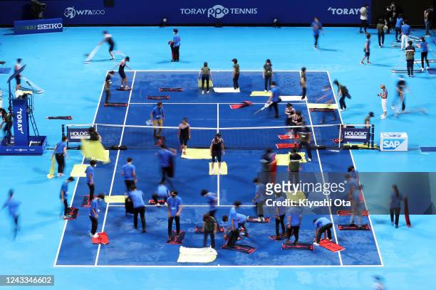 Ball kids and officials attempt to dry the court as rainfall suspends the Singles first round match between Wang Qiang of China and Elise Mertens of...