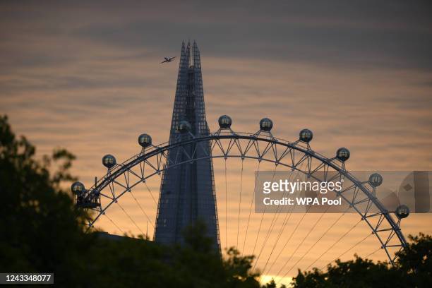 Passenger plane flies behind the Shard with The London Eye silhouetted at sunrise on the day of the State Funeral Service for Queen Elizabeth II on...