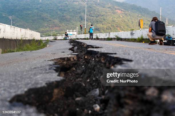 People walk on a collapsed bridge after a magnitude 6.8 earthquake hitting Taiwan caused severe damages to buildings, bridges and different...