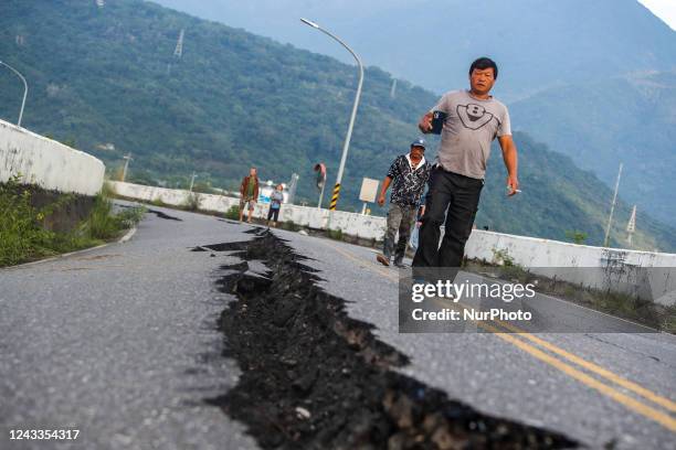 People walk on a damaged road with fissures after a magnitude 6.8 earthquake hitting Taiwan caused severe damages to buildings, bridges and different...