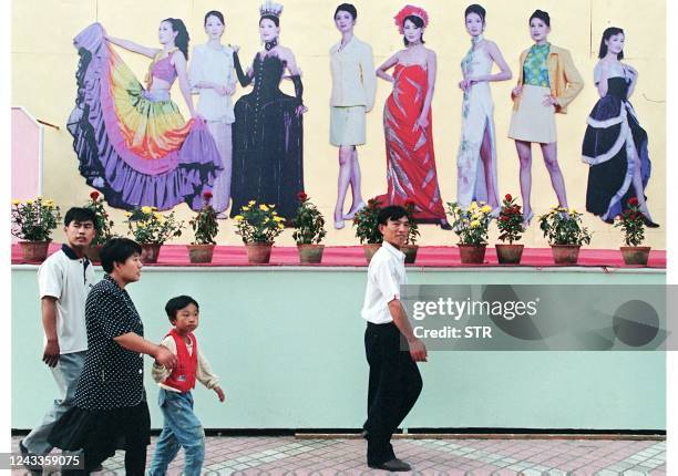 People walk pass an advertisement of the latest Chinese textiles and fashion, one of China's largest export product, in the northeastern industrial...