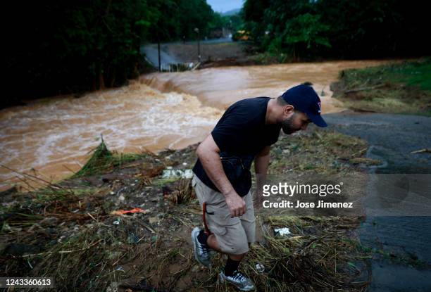 An unidentified man walks away from the overflooded Turabo river on September 19, 2022 in Caguas, Puerto Rico. Hurricane Fiona struck this Caribbean...