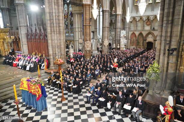 The coffin of Queen Elizabeth II, draped in the Royal Standard with the Imperial State Crown and the Sovereign's Orb and Sceptre, is carried by the...