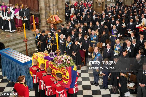 The coffin of Queen Elizabeth II, draped in the Royal Standard with the Imperial State Crown and the Sovereign's Orb and Sceptre, is carried by the...