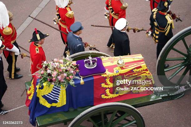 The State Gun Carriage carries the coffin of Queen Elizabeth II, draped in the Royal Standard with the Imperial State Crown and the Sovereign's orb...