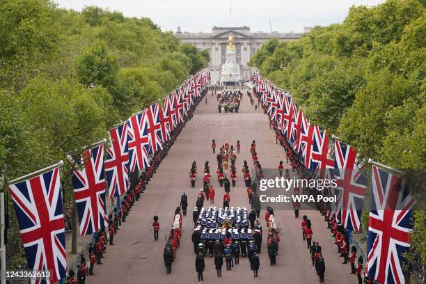 The State Gun Carriage carries the coffin of Queen Elizabeth II, draped in the Royal Standard with the Imperial State Crown and the Sovereign's orb...