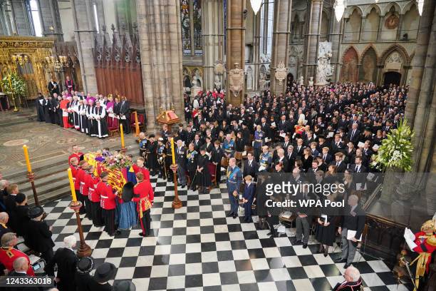 The coffin of Queen Elizabeth II, draped in the Royal Standard with the Imperial State Crown and the Sovereign's Orb and Sceptre, is carried by the...