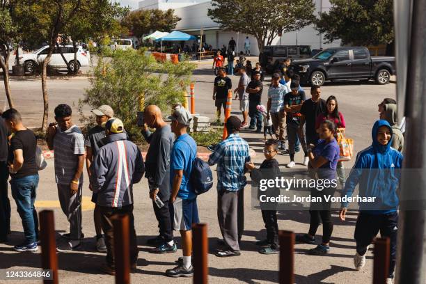 Groups of migrants wait outside the Migrant Resource Center to receive food from the San Antonio Catholic Charities on September 19, 2022 in San...