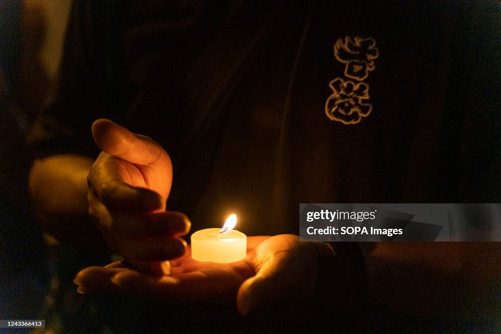 Member of the public holds a lit candle as he pays tribute...