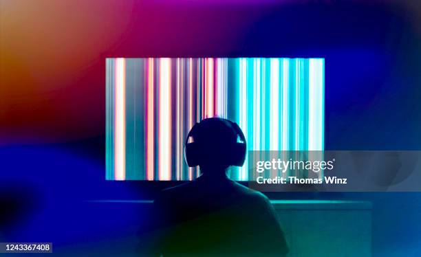 silhouetted person with headphones watching large tv screen - binge watching stock pictures, royalty-free photos & images