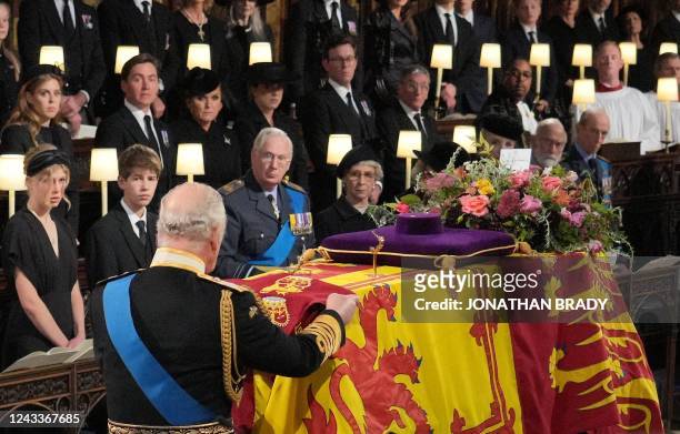 Britain's King Charles III places the the Queen's Company Camp Colour of the Grenadier Guards on the coffin during the Committal Service for...