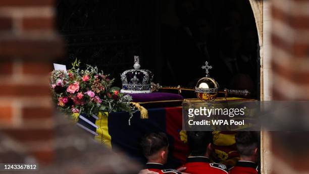 The Bearer Party take the coffin of Queen Elizabeth II, draped in a Royal Standard and adorned with the Imperial State Crown and the Sovereign's orb...