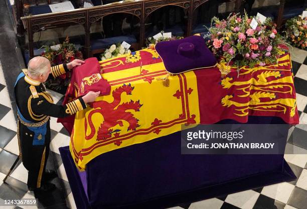 King Charles III places the the Queen's Company Camp Colour of the Grenadier Guards on the coffin during the Committal Service for Britain's Queen...