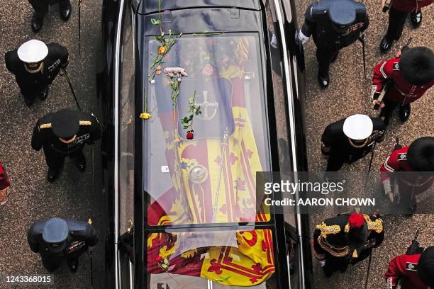 Flowers lay on the roof of the State Hearse carrying the coffin of Queen Elizabeth II, as it arrives at Windsor Castle on September 19 ahead of the...