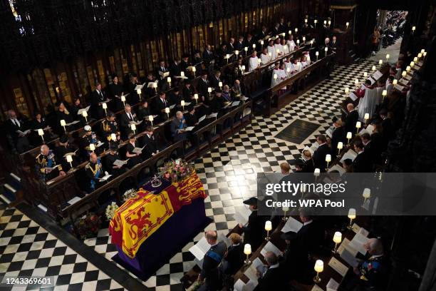The coffin of Queen Elizabeth II draped in the Royal Standard with the Imperial State Crown and the Sovereign's orb and sceptre, in front of the Earl...