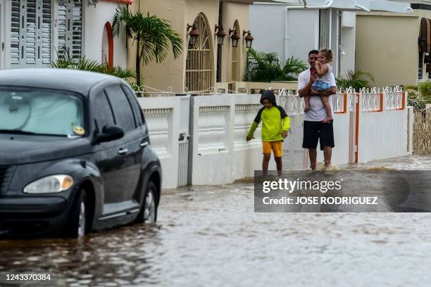 Man and two children walk in a flooded street after the passage of Hurricane Fiona in Salinas, Puerto Rico, on September 19, 2022. - Hurricane Fiona...