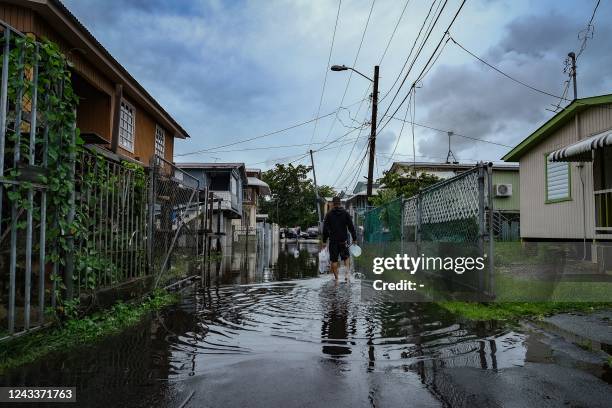 Man walks down a flooded street in the Juana Matos neighborhood of Catano, Puerto Rico, on September 19 after the passage of Hurricane Fiona. -...