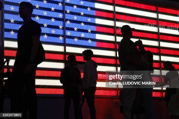 People stand in front of a US flag on a screen in Times Square in New York on September 19, 2022.