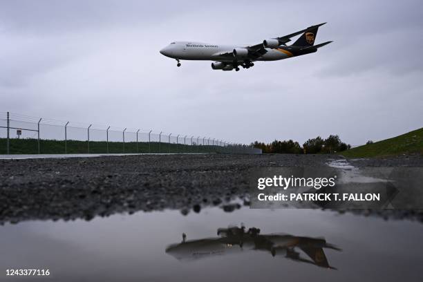 United Parcel Service Boeing 747 cargo aircraft is reflected in a puddle as it lands in the rain at the Ted Stevens International Airport in...