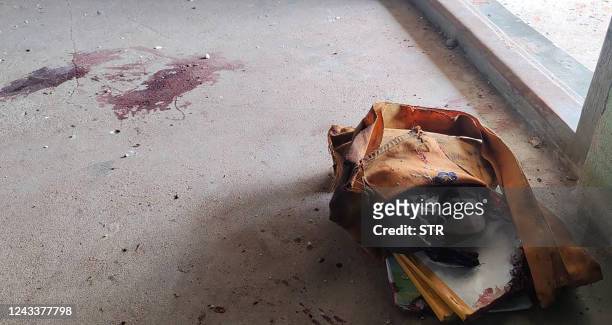 This photo taken on September 17, 2022 shows bloodstains on the floor next to an abandoned backpack in a damaged school building in Depeyin township...