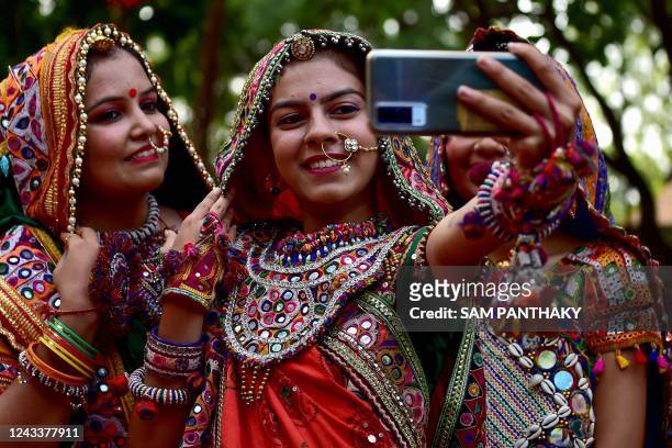 Participants from an art group wearing traditional dresses pose for a selfie during Garba dance rehearsals ahead of the Navratri festival in...