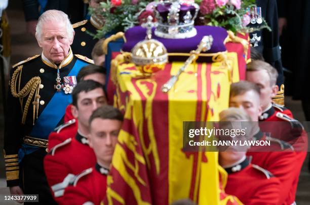 King Charles III and members of the royal family follow the coffin of Queen Elizabeth II, draped in the Royal Standard with the Imperial State Crown...