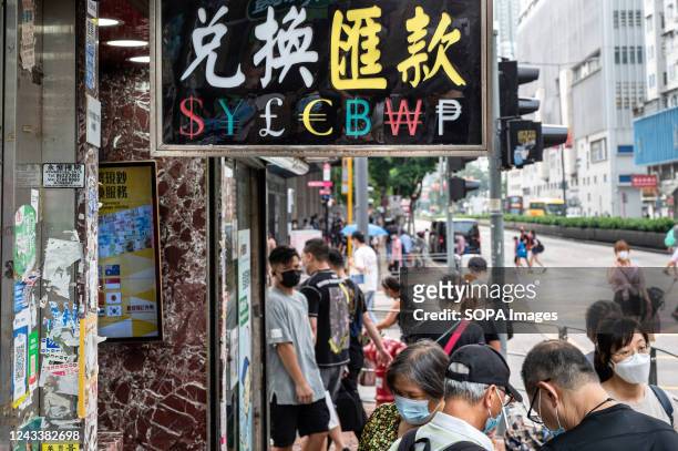 Pedestrians walk past a currency money exchange shop with a sign offering: US Dollar , Japanese Yen , British Pound , Euro , Bitcoin , Korean Won ,...
