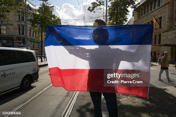 An anti-government protester holds a Dutch flag upside down on Prinsjesdag, the day of the opening of parliament on September 20, 2022 in The Hague,...