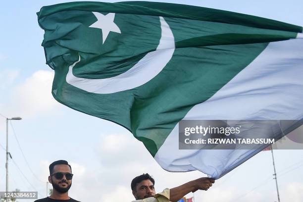 Cricket fans hold Pakistan flag as they wait to enter the National Cricket Stadium before start the first Twenty20 international cricket match...