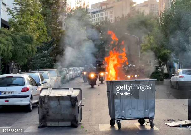Picture obtained by AFP outside Iran shows a bin burning in the middle of an intersection during a protest for Mahsa Amini, a woman who died after...