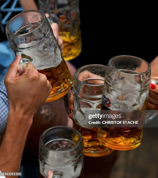 Festival-goers clink with beer mugs in a beer tent during the Oktoberfest beer festival at the Theresienwiese fairground in Munich, southern Germany,...