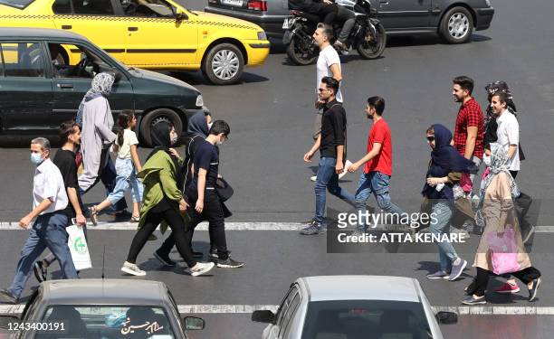 Iranians cross an intersection in the capital Tehran on September 21, 2022. - Protests spread to 15 cities across Iran overnight over the death of...