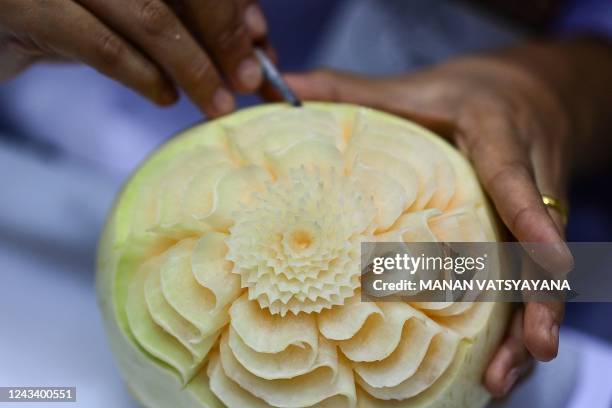 Participant carves patterns into a melon during a fruit and vegetable carving competition at the 26th Thailand International Culinary Cup in Bangkok...