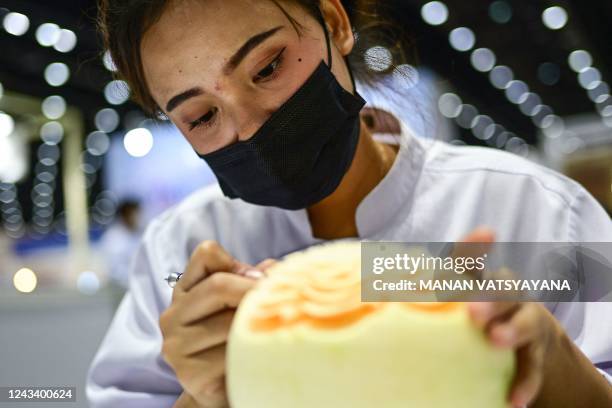 Thai participant carves patterns into a melon during a fruit and vegetable carving competition at the 26th Thailand International Culinary Cup in...