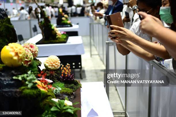Visitors take photographs of carved fruits and vegetables decoration during a fruit and vegetable carving competition at the 26th Thailand...