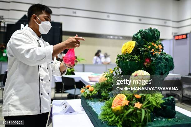 Thai participant sprays water on his carved fruits and vegetables decoration during a fruit and vegetable carving competition at the 26th Thailand...