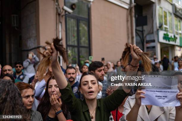 Nasibe Samsaei, an Iranian woman living in Turkey, holds up her hair after cutting it off with a pair of scissors, during a protest outside the...
