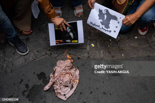 An Iranian woman living in Turkey, burns a headscarf, during a protest outside the Iranian consulate in Istanbul on September 21 following the death...
