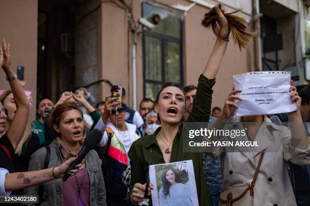 Nasibe Samsaei, an Iranian woman living in Turkey, holds up her ponytail after cutting it off with scissors, during a protest outside the Iranian...