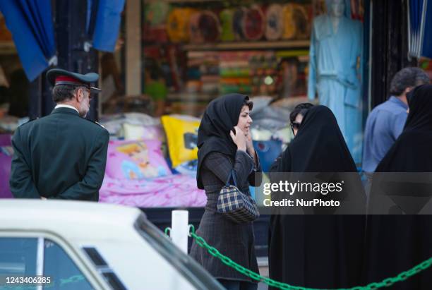 April 23, 2007 file photo shows, An Iranian woman adjusts her scarf as two veiled morality policewomen talk to them in Tehran. Thousands of Iranians...