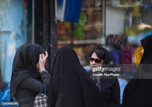 April 23, 2007 file photo shows, An Iranian woman adjusts her scarf as two veiled morality policewomen talk to them in Tehran. Thousands of Iranians...