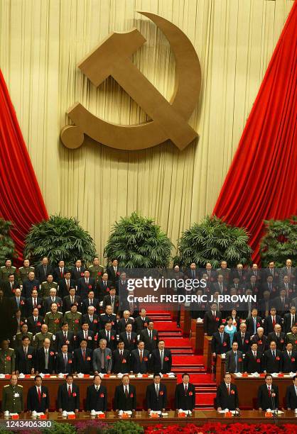 Delegates and China's top leaders stand for the national anthem beneath a Communist hammer and sickle emblem, 08 November 2002 at the Great Hall of...